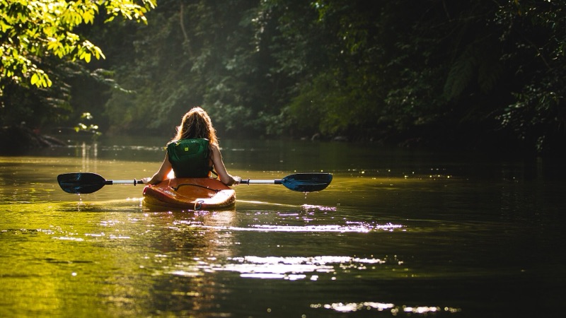 A kayaker paddling up a calm, forest-lined river at Drake Bay on the Osa Peninsula