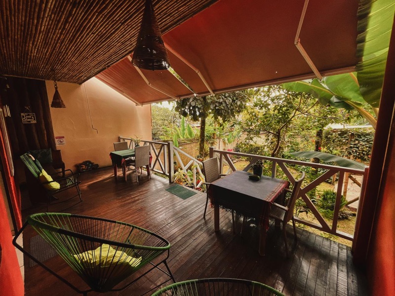 Covered wooden terrace with tables looking onto the garden at Hotel Casa de Lis