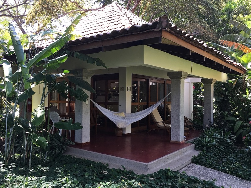A garden bungalow with a hammock on its porch at a hotel in Tamarindo, Costa Rica